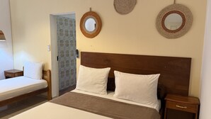 A bedroom with a wooden headboard, two white pillows, a brown bedspread, and two bedside tables.