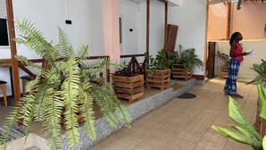 A covered outdoor area with wooden planters, a tiled floor, and a person standing.