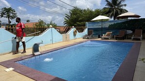 A swimming pool with a water feature, lounge chairs, and a palm tree in the background.