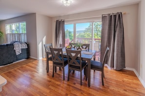 A dining area with a table and chairs, a sofa, and a view through a window.