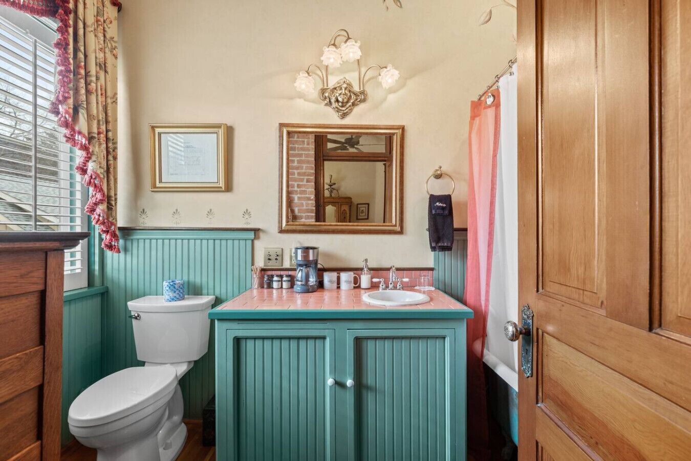 A bathroom with a toilet, sink, vanity, mirror, and a shower curtain.