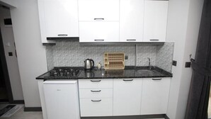 Una cocina compacta con armarios blancos, una encimera negra, una estufa integrada y un fregadero.