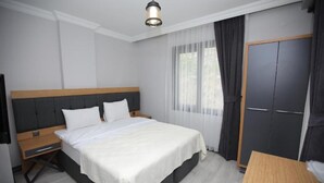 Un dormitorio con cama, mesita de noche, armario y mesa.