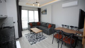 Un espacio habitable moderno con cocina, comedor y un sofá gris con cojines rojos.