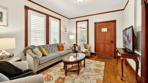 A living room with a sofa, armchair, coffee table, and television. - Whimsy on B | 2BR Steps to Downtown (Ashland)