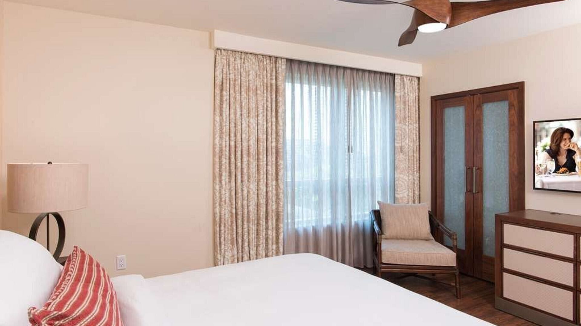 Een hotelkamer met een bed, een stoel, een bureau, een lamp en een televisie.