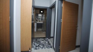 Ein Flur, der zu einem Badezimmer mit Dusche, Toilette und Waschbecken führt.