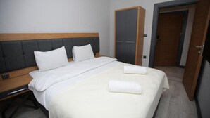 Ein Hotelzimmer mit Bett, Nachttisch, Schrank und offener Tür zu einem anderen Raum.