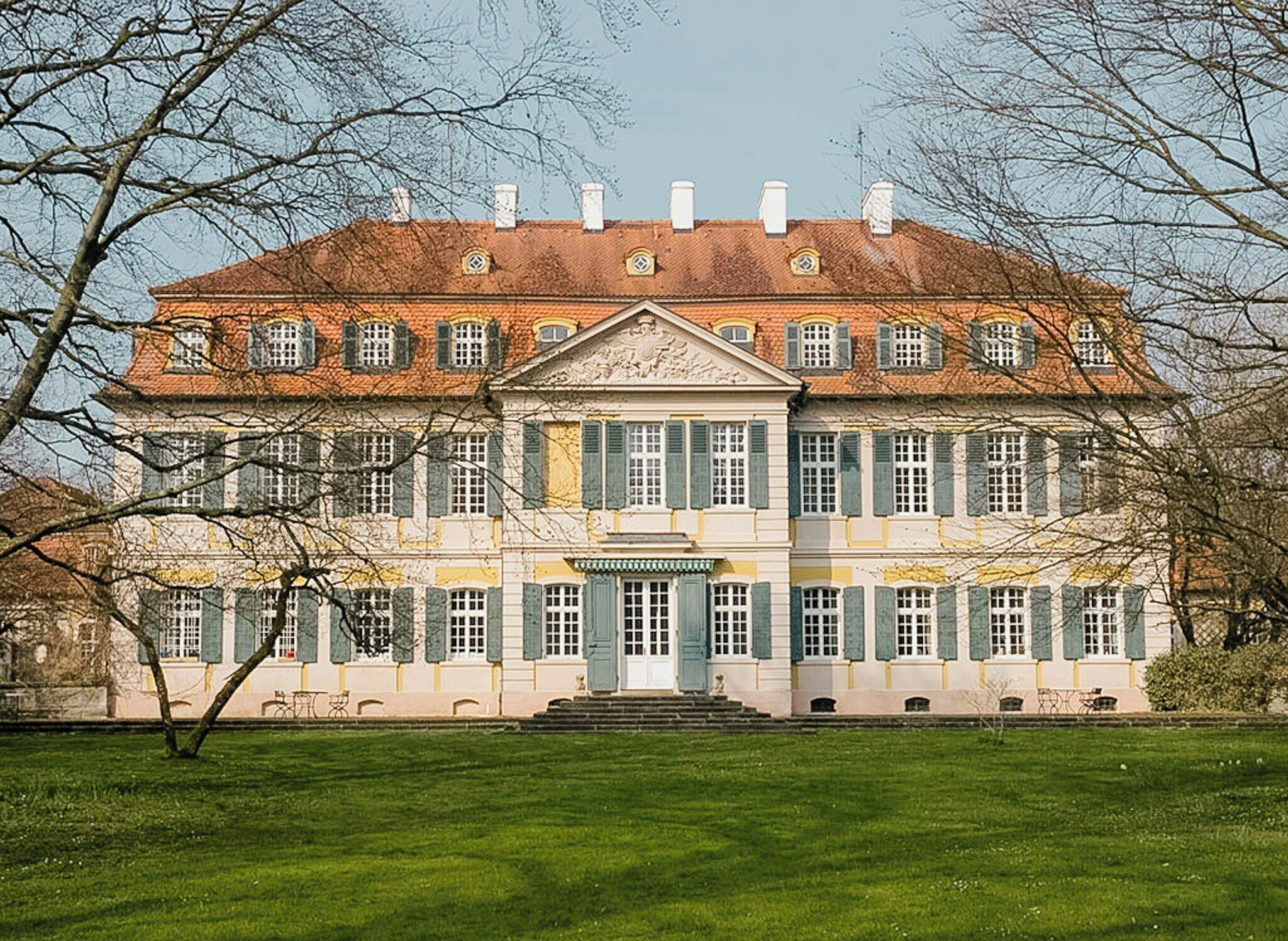 Een groot, historisch gebouw met een symmetrische gevel, meerdere ramen en een centrale ingang.