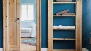Ein Zimmer mit Holzboden, einer blauen Wand und einer eingebauten Holzregaleinrichtung mit gefalteten Decken.