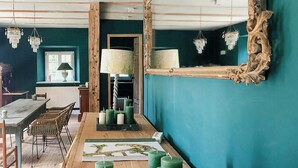 Ein Zimmer mit türkisfarbenen Wänden, einem Holztisch mit Kerzen, einem Spiegel mit aufwendigem Rahmen und einer Kristallleuchter.