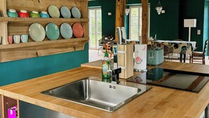 Eine Küche mit Holzböden, einer Edelstahlspüle und einem Essbereich mit Tisch und Stühlen.