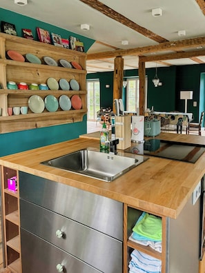 Eine Küche mit Holzböden, einer Edelstahlspüle und einem Essbereich mit Tisch und Stühlen.