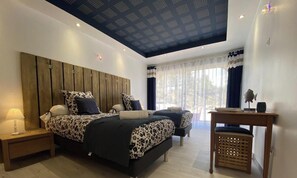 Un dormitorio con dos camas, un techo con diseño geométrico y una ventana con cortinas translúcidas.