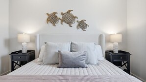 Un dormitorio con una cama, dos mesitas de noche y tres adornos en la pared.