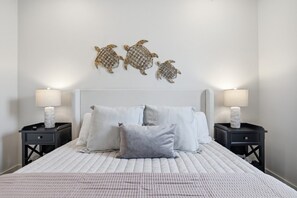 A bedroom with a bed, two nightstands, and three wall-mounted decorative items.