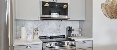 A modern kitchen with a stainless steel refrigerator, a black stove, and a coffee maker on the countertop.