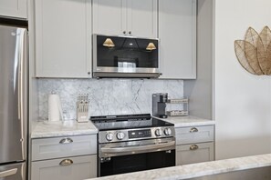 Una cocina moderna con un refrigerador de acero inoxidable, una estufa negra y una cafetera en la encimera.