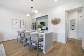 Een moderne keuken met een centraal eiland, barstoelen, een koelkast en een decoratief wandpaneel.