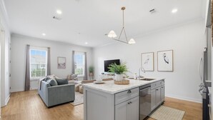 Una cocina moderna con una isla central, armarios grises y una zona de comedor con un sofá gris.