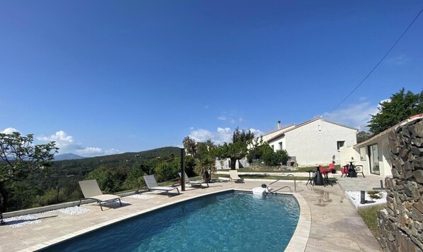 A swimming pool with lounge chairs, a stone wall, and a building with a white facade. - Bonica Vista - 6 people (OMS)