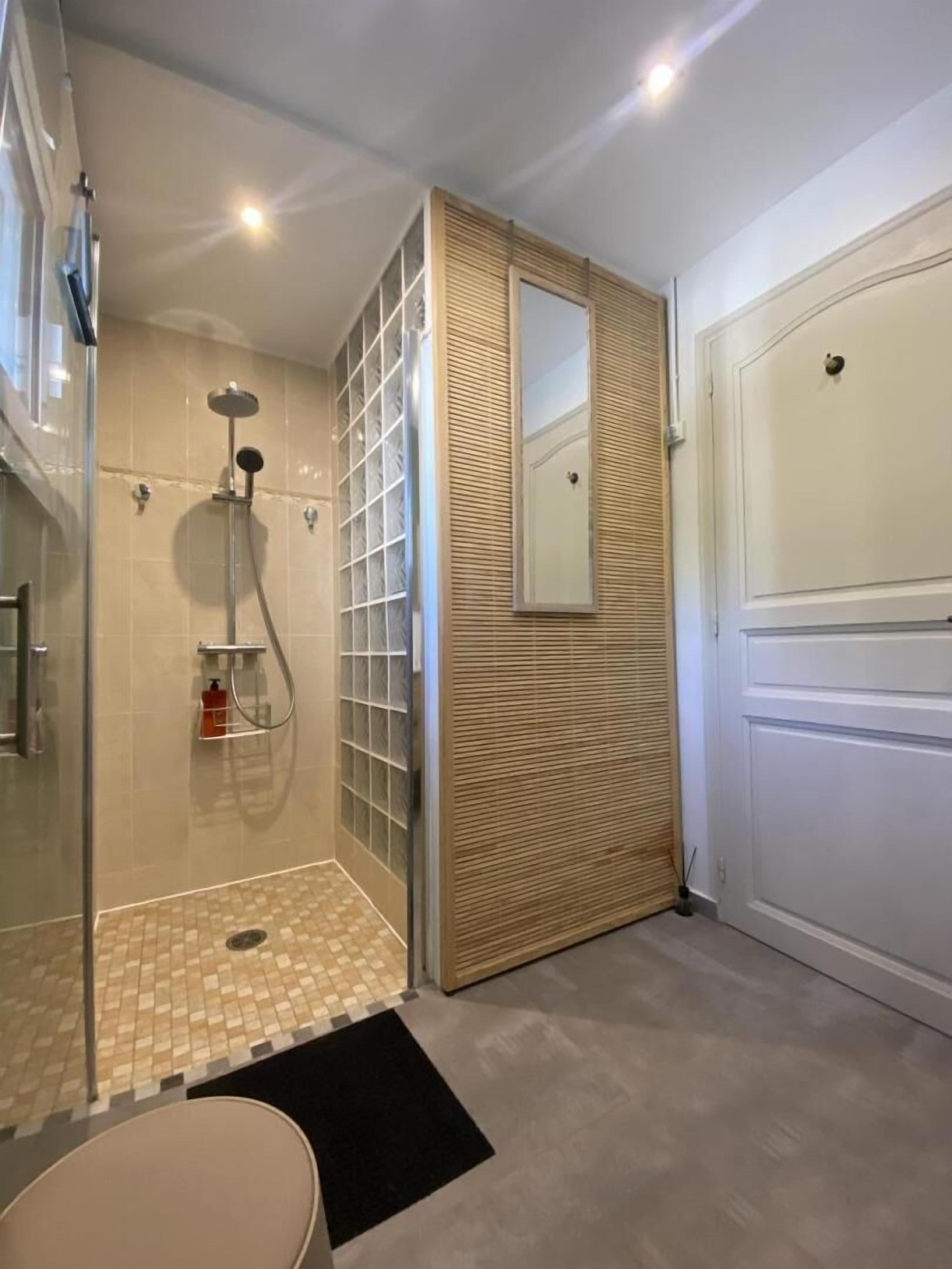 Un baño moderno con cabina de ducha de vidrio, suelo de baldosas y pared de paneles de madera.