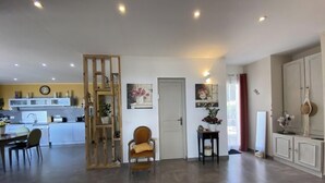A modern kitchen with white cabinets, a dining area with a table and chairs, and a living space with a sofa and a chair. - Bonica Vista - 6 people (OMS)