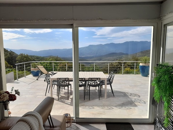 Ein Balkon mit Tisch, Stühlen und einer Sitzecke, mit Blick auf Berge.
