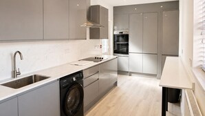 Una cocina moderna con lavadora integrada, horno doble y un amplio ventanal.
