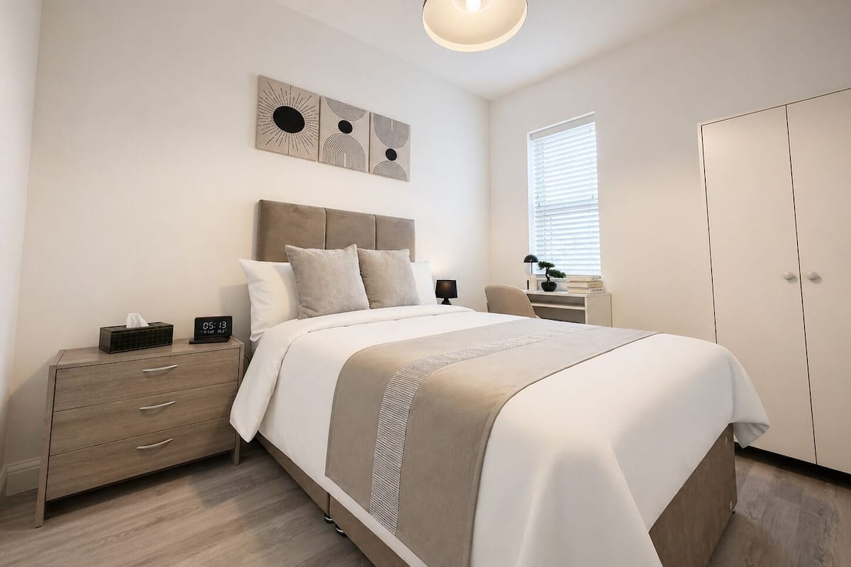 A bedroom with a bed, bedside table, lamp, and a wardrobe.