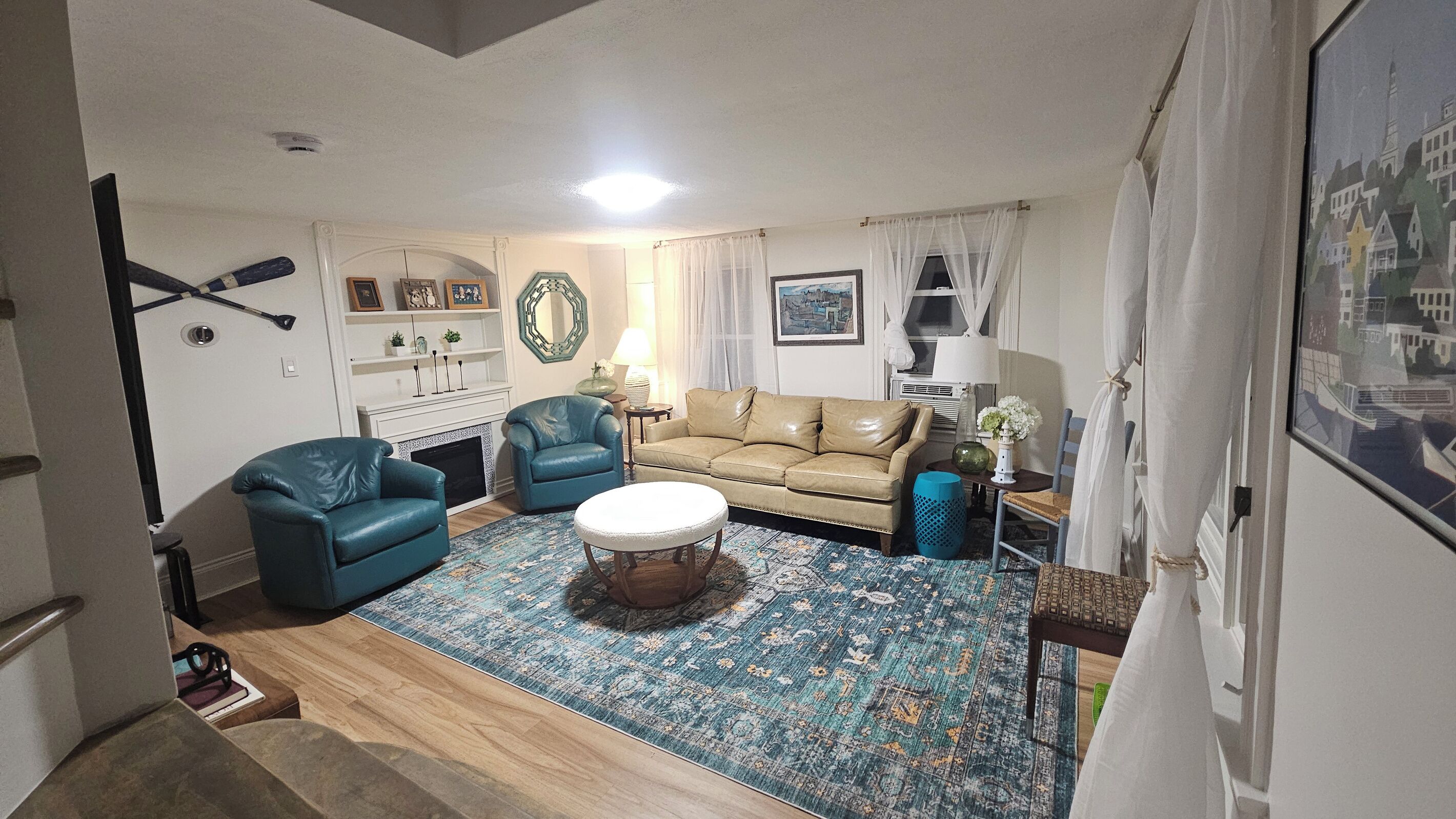 A living room with a sofa, two armchairs, a coffee table, a patterned rug, and a fireplace.