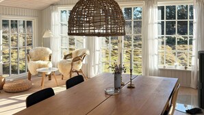 Ein Essbereich mit Holztisch, Stühlen und einer gewebten Pendelleuchte.