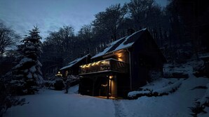 Eine Holzhütte mit geneigtem Dach und beleuchtetem Eingang.