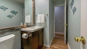 A bathroom with a white sink, two towel racks, a toilet, and a mirror. - Horizon South 75C Resort-style (Panama City Beach)