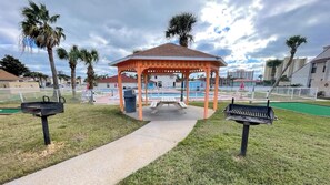 A gazebo with a pool, grill stations, and a clear sky. - Horizon South 75C Resort-style (Panama City Beach)