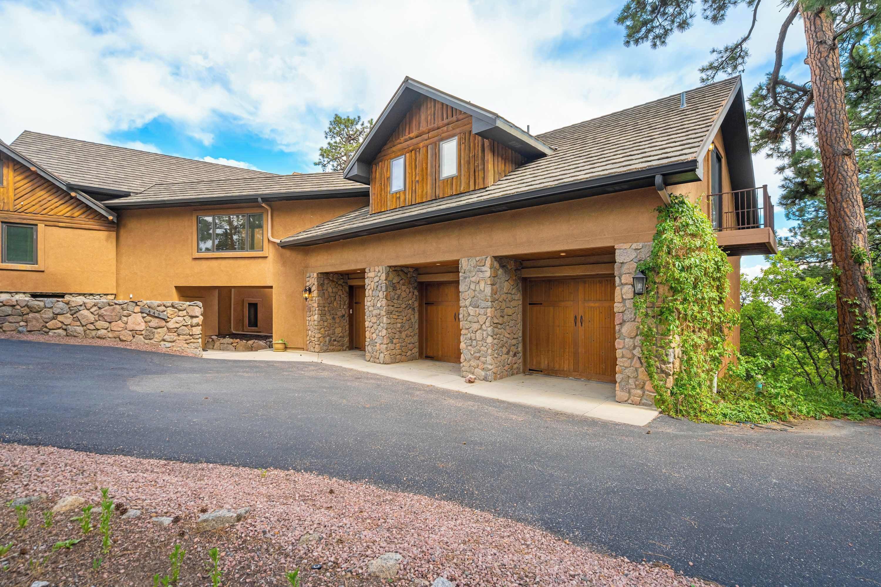 Une maison à deux étages avec une façade en pierre, un garage et une allée.