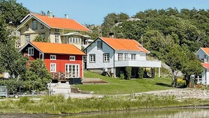 Udsigt over en sø med huse, der spejles i vandet, omgivet af grøn vegetation.