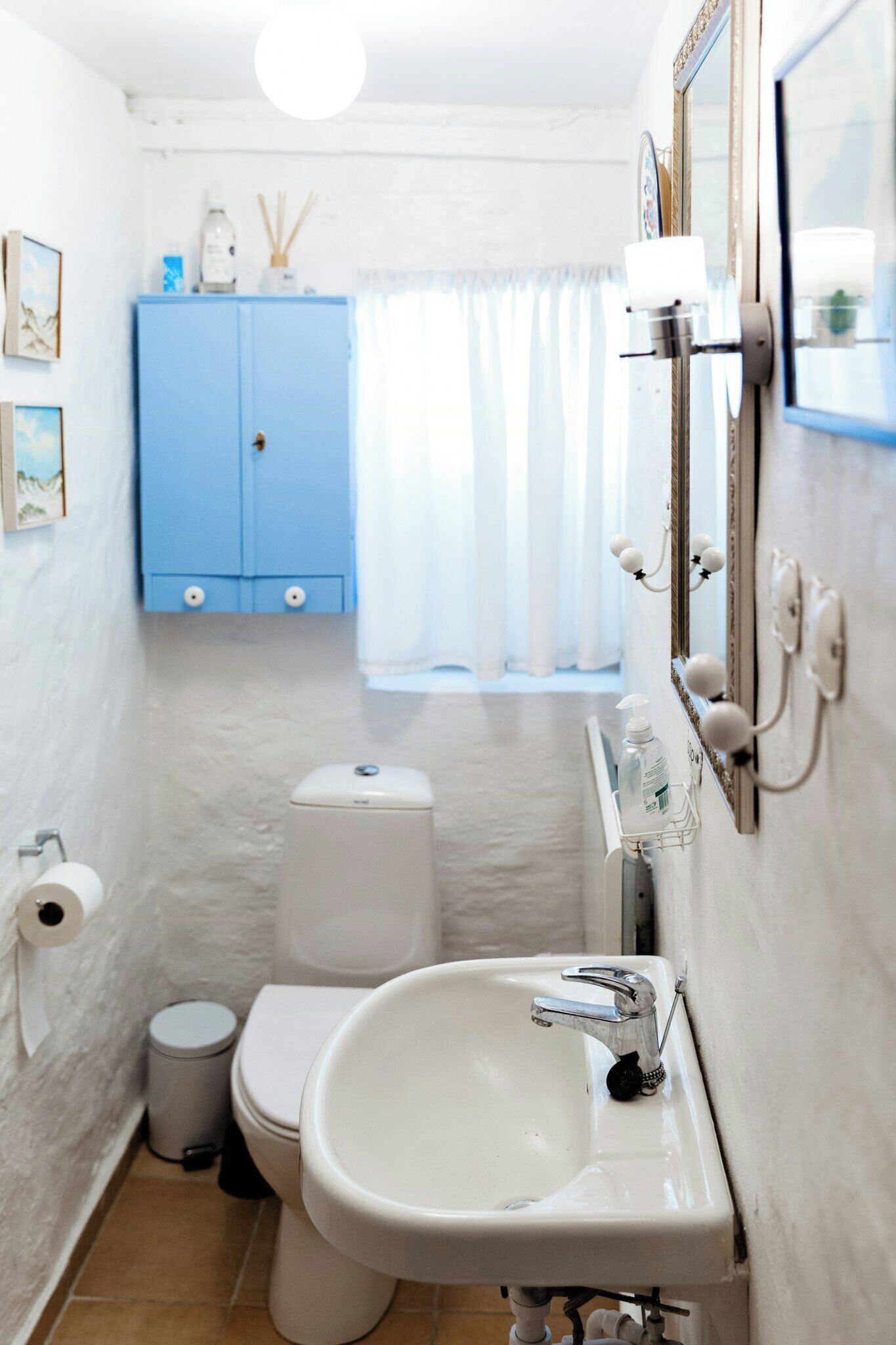 Een badkamer met een witte wastafel, toilet en blauwe kast.