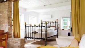 Una camera da letto con un letto a baldacchino, una parete in mattoni e una finestra con tende.