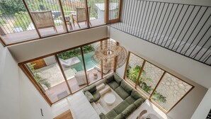 A modern interior with a sectional sofa, a round table, and a view of the outdoors. - Cozy villa, prime Uluwatu, actual walking distance (Badung Regency)