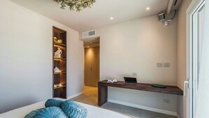 Un dormitorio con cama, almohadas, escritorio y armario.