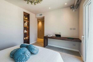 Ein Schlafzimmer mit einem Bett, Kissen, einem Schreibtisch und einem Kleiderschrank.