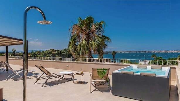 Terraza en la azotea con piscina, sillas de descanso y una palmera.