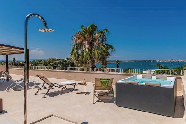 Eine Dachterrasse mit Pool, Liegestühlen und einer Palme.