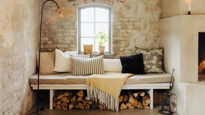 Un rincón acogedor con un banco, almohadas, una manta y una ventana con una planta.