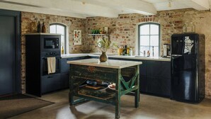 Una cocina con paredes de ladrillo, una mesa antigua y electrodomésticos modernos.
