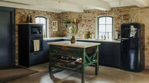 Eine Küche mit Backsteinwänden, einem Vintage-Tisch und modernen Geräten.