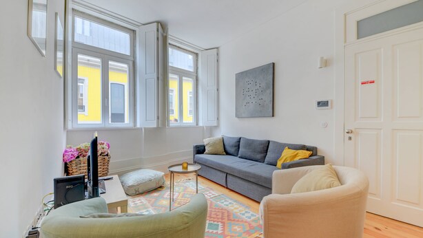 Una sala de estar con un sofá, sillones, una mesita y un televisor.