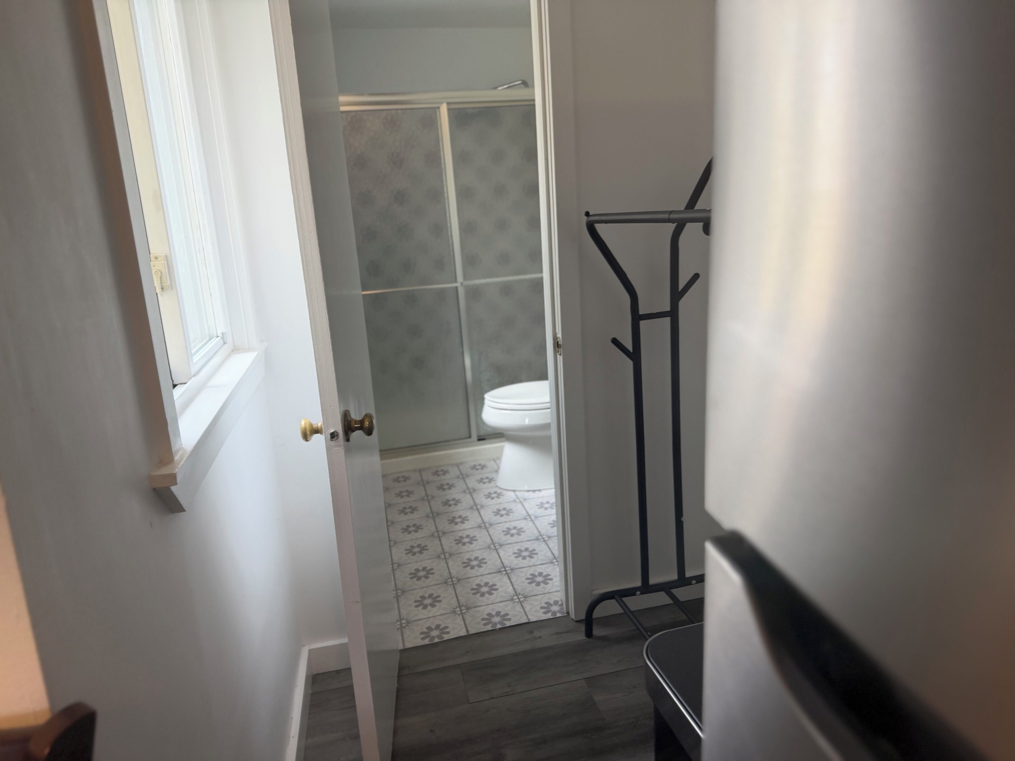 A bathroom with a toilet, shower, and a towel rack.