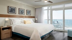 A hotel room with a large bed, a nightstand, a desk, and a balcony with a view of the ocean. - Myrtle Beach Ocean View Stay with Pools & Spacious 3BR Plus Suite (Myrtle Beach)